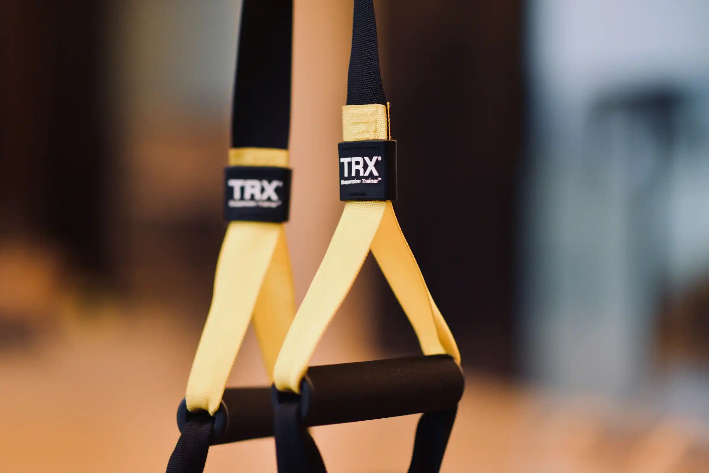 Correas de suspensión TRX amarillas colgando, listas para una sesión al aire libre